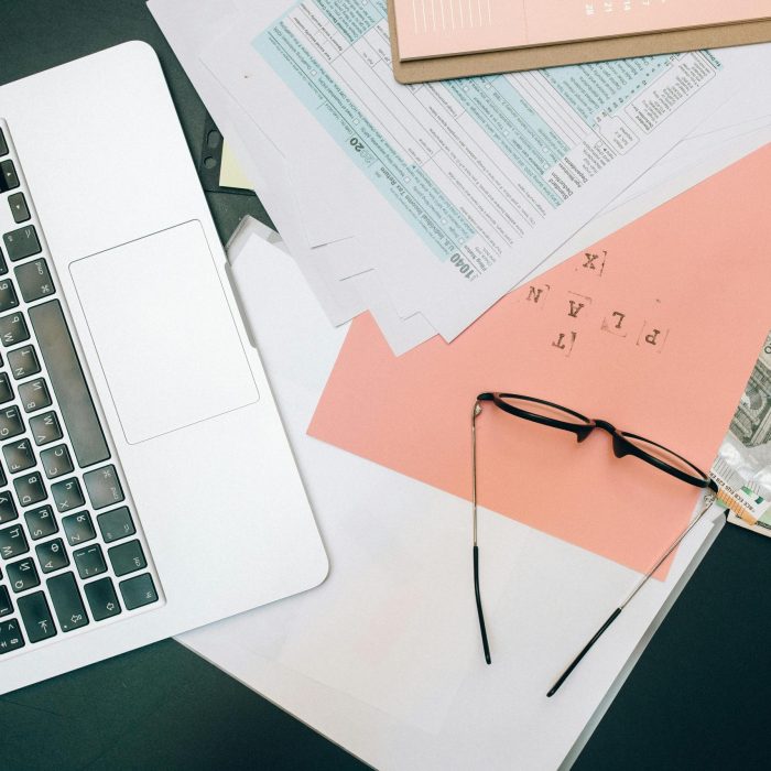 A tidy workspace featuring a laptop, documents, and eyeglasses for productivity.